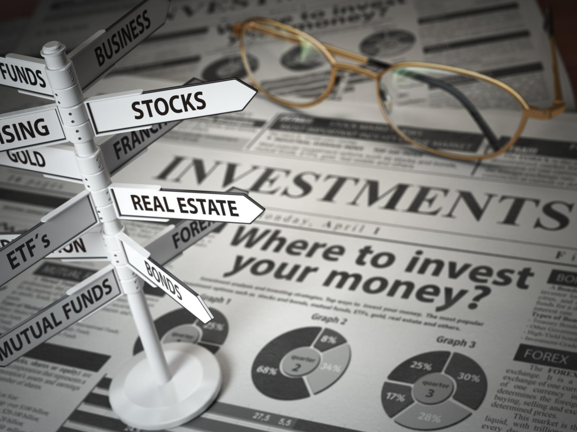 investment newspaper with road sign to stocks real estate etc