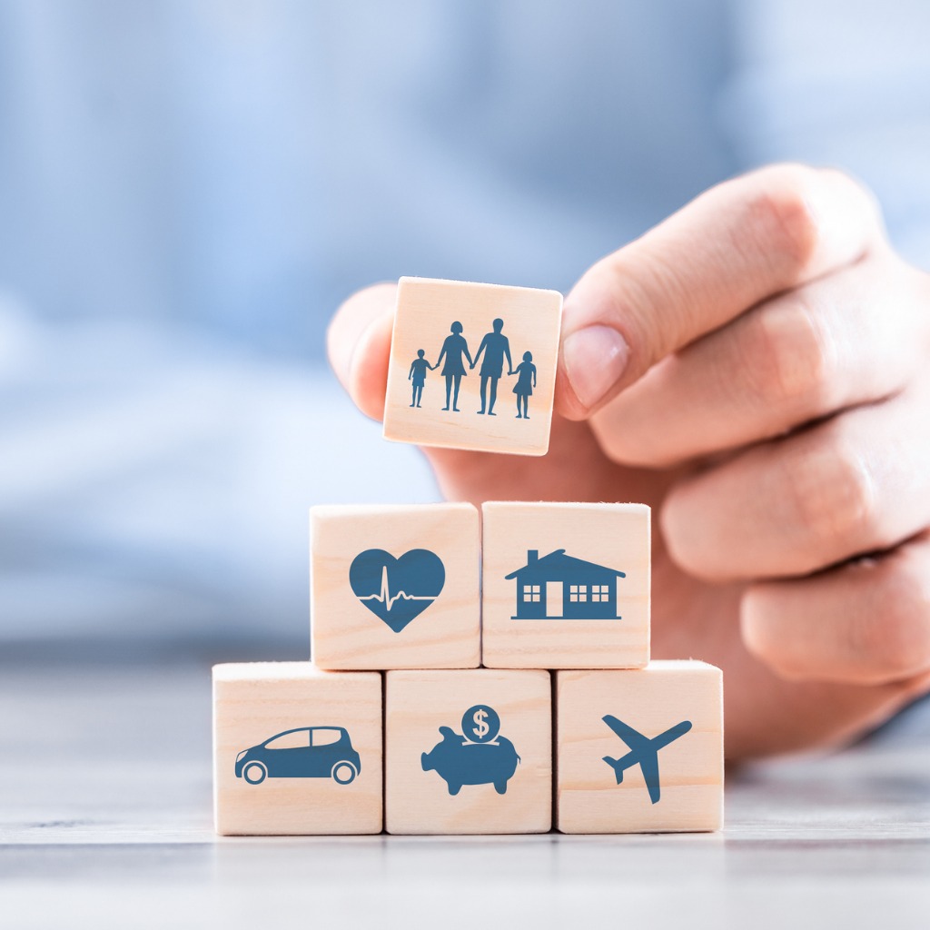 hand stacking small wooden blocks of insurance-related icons